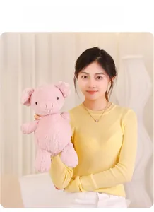 Close-up of a soft pink pig plush toy held by a model in a warm interior setting