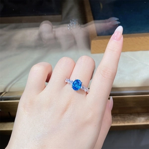 Macro shot of an oval blue sapphire ring with sparkling side stones on a model's hand