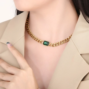 Detail van een gouden Cubaanse ketting met een vierkant smaragd kristal om de nek
