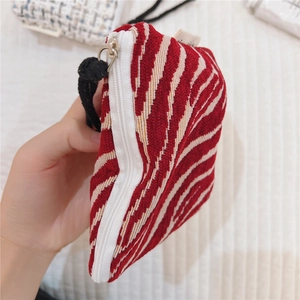 Macro detail of red and white striped fabric coin purse with white zipper and cotton cord