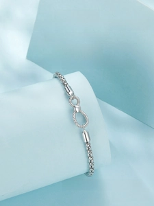 Detail of 925 sterling silver infinity bracelet displayed on minimalist blue props