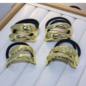 Set of 4 minimalist gold metal hair ties with diverse textures on a white jewelry tray