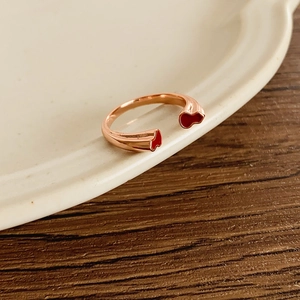 Détail macro d'une bague ouverte or rose avec émail rouge sur plateau en céramique