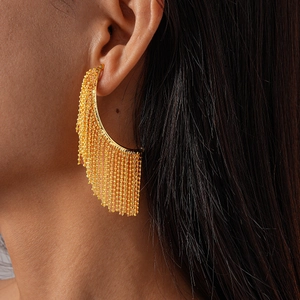 Close-up of elegant gold tassel earrings with metallic bead strands on model's ear