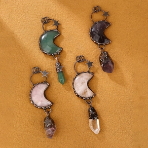 Retro bronze crescent moon pendants with colorful crystals and star charms displayed on paper