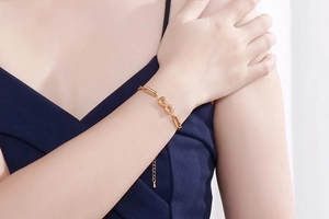 Detail of gold infinity symbol bracelet with mixed chain design on female wrist
