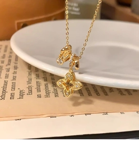 Detail of clover pendant necklace with zircon rings resting on a white ceramic plate