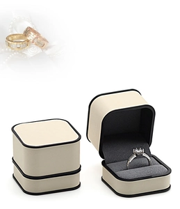 Cream leather jewelry box with black trim showing open and closed views for rings