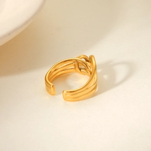 Detailed view of an 18K gold knot design open ring on a textured beige surface