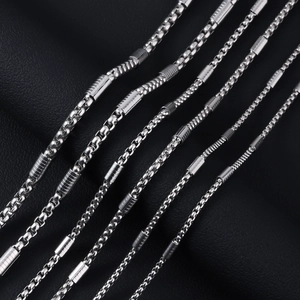 Macro detail of polished stainless steel box chain necklace on black leather surface