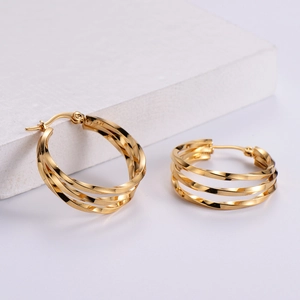 Detailed view of layered gold irregular spiral hoop earrings on a stone base
