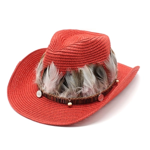 Detail of red woven cowboy hat featuring ethnic feathers and retro silver pendants