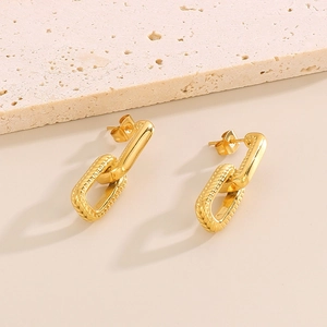 Macro shot of gold-plated chain link earrings on textured stone for high-end look