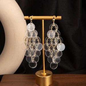 Detail of bohemian drop earrings with clear acrylic discs on gold jewelry display stand