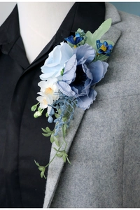 Detailed view of a handmade blue and white floral boutonniere on a gray suit lapel