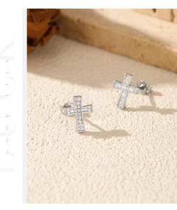 Detail of silver cross stud earrings with small moissanite stones on a textured stone