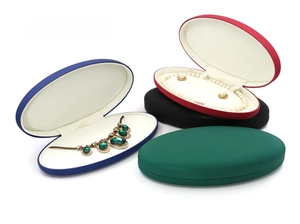 Detailed view of oval faux leather jewelry boxes in four colors with pearl necklace slots