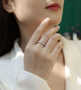 Close-up of minimalist silver band ring with pavé moissanite stones on a female hand