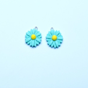 Detailed macro view of mint green resin daisy charms with yellow centers and silver loops