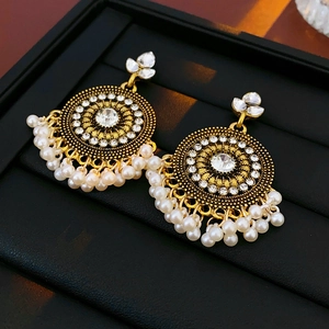 Dettaglio di orecchini Jhumka vintage dorati con cristalli e nappe di perle bianche