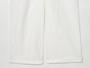 Gros plan détaillé du bas de pantalon en nylon blanc montrant les coutures et le tissu