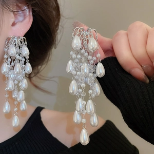 Detail of silver drop tassel earrings featuring cascading white pearls and crystal beads