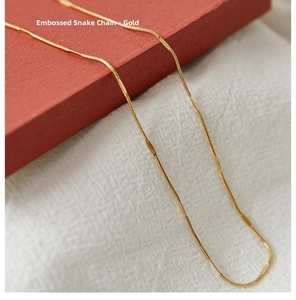 Macro view of detailed embossed gold snake chain necklace with fine metallic texture