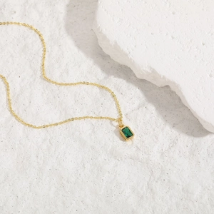 Gros plan d'un collier en or avec pendentif en zircon émeraude de forme carrée