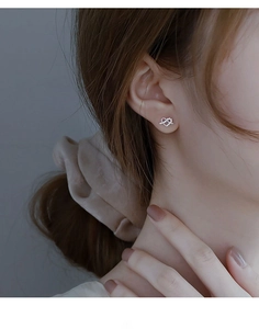 Close-up of 925 sterling silver heart-shaped zircon earrings worn on an earlobe