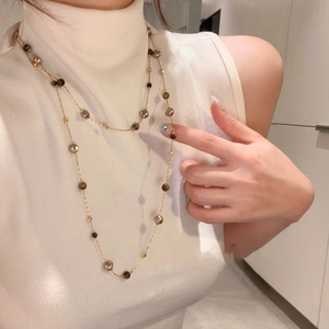 Collier de perles œil de tigre plaqué or 18 carats superposé sur un haut blanc sans manches