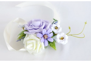 Detail of bridal wrist corsage with purple and white silk roses on ivory satin ribbon