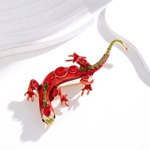 Détail macro de la broche lézard avec émail rouge et accents de strass verts étincelants