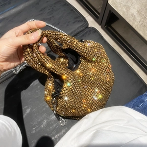 Detail of gold rhinestone mini bucket bag with sparkling crystals and metal handle