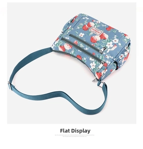 Detail of light blue floral crossbody bag featuring double front zip pockets and strawberry print