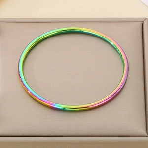 Close-up of a 3mm rainbow gradient stainless steel thin bangle on a gold textured box