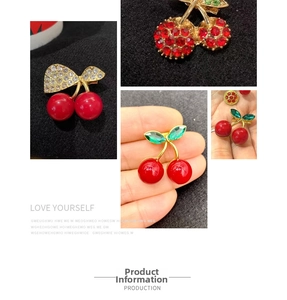 Detailed macro view of cherry brooches with rhinestones and gold-plated alloy finish
