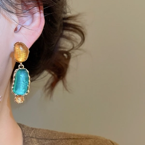 Nahaufnahme von Vintage-Resin-Ohrhängern mit Goldrahmen, getragen von einem Modell