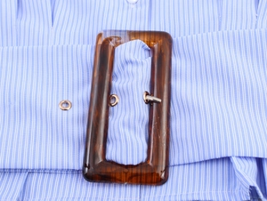 Detail of blue striped shirt featuring a wide belt with tortoiseshell buckle and metal eyelets