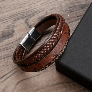 Close-up of brown braided leather bracelet with silver magnetic clasp on wooden surface