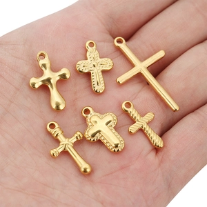Sechs verschiedene goldene Edelstahl-Kreuzanhänger für DIY-Schmuck in der Hand