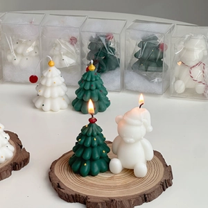 Close-up of Christmas tree and bear candles on natural wood slice with festive packaging
