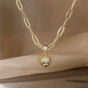 Close-up of golden bear pendant with micro-inlaid zircons on a paperclip style chain
