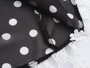 Détail macro du tissu à pois noir et blanc avec coutures délicates en dentelle blanche