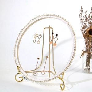 Detailed view of jewelry display stand with pearl trim and gold base holding earrings