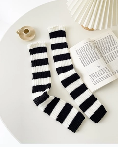 Close-up of black and white striped leg warmers with delicate ruffle trim edge