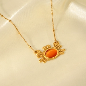 Detail of a gold crab pendant with orange cat eye stone on a beaded silk chain