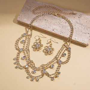 Close-up of golden fringe flower necklace and earrings set with sparkling rhinestones