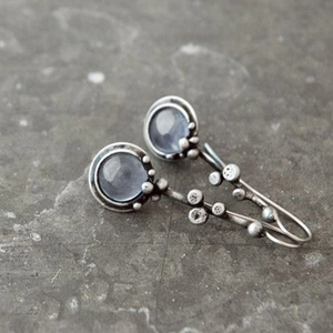 Détails macro des boucles d'oreilles pierre de lune bleue au design branche vintage
