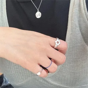 Detailed view of layered 925 sterling silver flower ring and embossed coin necklace set