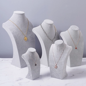 Set of five grey velvet necklace display stands in various heights on marble